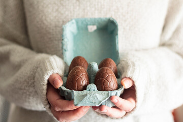Fototapeta na wymiar Close up of woman holding carton egg box with easter chocolate eggs