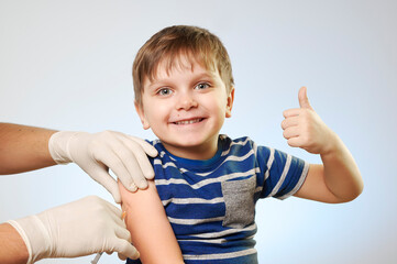 Vaccination . Female doctor vaccinating cute little boy on blue background, closeup.