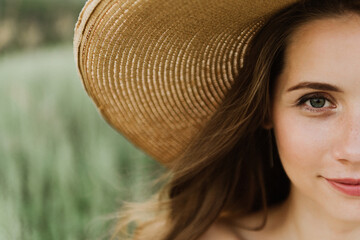 Young beautiful woman in boho style dress and hat on the field with wheat.