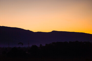 Golden morning sky in winter, misty high mountain background. Silhouette hills and misty in the morning at Chaiyaphum,Thailand.