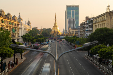 General view of Sule Pagoda Buddhist temple and stupa, decorated in gold, surrounded by traffic, from the Sule Paya Road Pedestrian Bridge, in Downtown Yangon. - obrazy, fototapety, plakaty