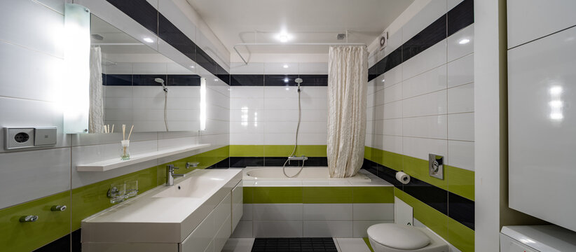 Contemporary Interior Of Bathroom In Modern Flat. Black And Green Tile. Sink And Mirror. Bath With Shower.