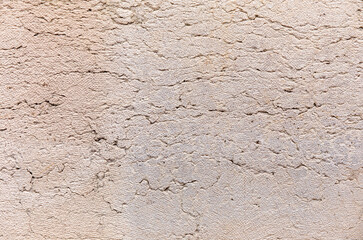 Old beige stucco wall with cracks texture