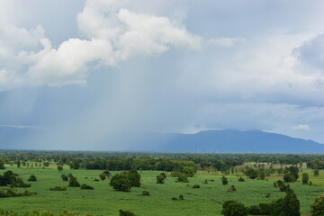 clouds over the mountains with raining in the front of it white and gray clouds and strong winds green farm land landscape in Thailand