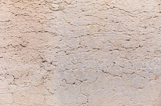Old beige stucco wall with cracks texture
