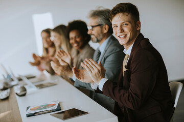 Multiethnic group of business people working together and applauding in after succesful meeting in...