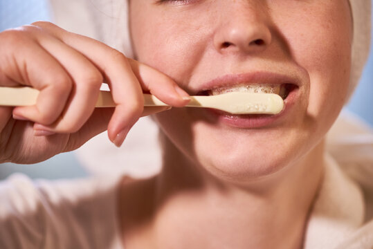 Close-up image of young woman brushing teeth after taking morning shower