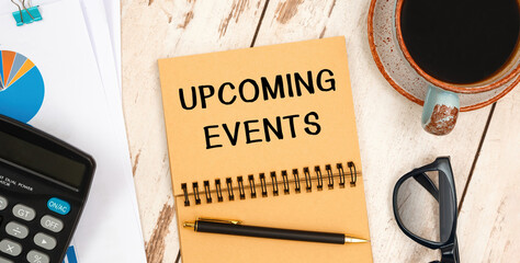 Notebook with text UPCOMING EVENTS near office supplies.