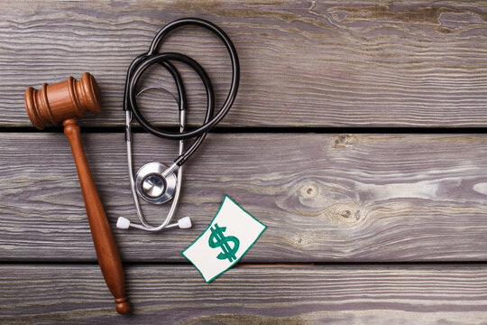 Judgement and healthcare concept. Wooden gavel and stethoscope on wooden desk.