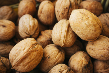 Walnut background. Natural walnuts texture. Nuts in shells. Stacked pile of wallnuts pattern.
