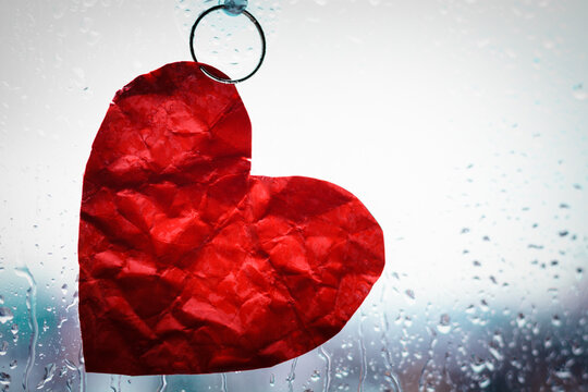 red paper heart fixed on a suction cup to glass with water drops