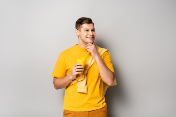 Smiling man holding takeaway coffee on grey background