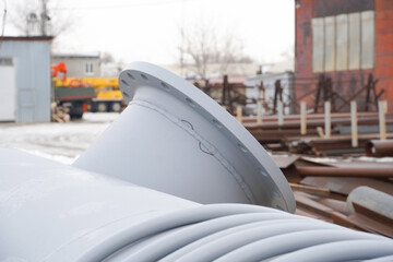Construction of a new reservoir and vessel with a diameter of 1000 mm for filling with gasoline and petroleum products at an oil refinery with a crane in the background
