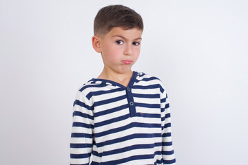 little cute boy kid wearing red stripped t-shirt against white wall with snobbish expression curving lips and raising eyebrows, looking with doubtful and skeptical expression, suspect and doubt.