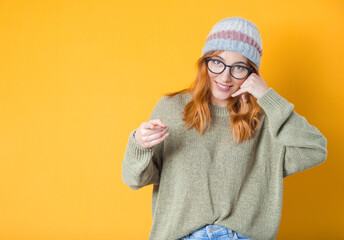 Call me. Woman gesturing at speaking on phone while looking to camera, isolated on yellow background. Woman on phone