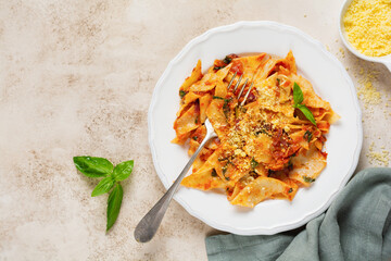 Pasta Maltagliati with classic tomato sauce, parmesan and basil on a rustic concrete light table background. Traditional Italian dish serving. Top view.