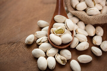 Pistachios in a wooden spoon. Sack with pistachios on a wooden table. (selective focus; close-up shot)