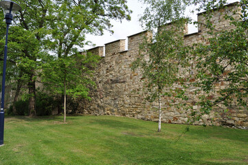 Fortress wall among trees on a summer day. Fragment of an ancient defensive wall. Picture