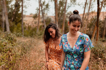 Fototapeta premium Two young lesbians walking in the woods wearing long dresses