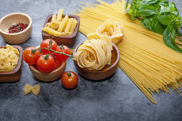 Mixed dried pasta selection on wooden background. composition of healthy food ingredients isolated on black stone background, top view, Flat lay.