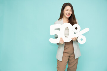 Portrait of Asian business woman showing and holding 50% number or Fifty percent isolated over light green background