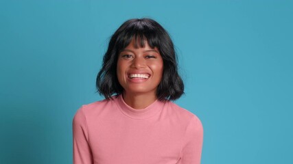 Hey, listen here. Positive dark skinned young woman looking at camera and exclaiming hey while standing on blue background. Concept of discounts important announcements and positive news.