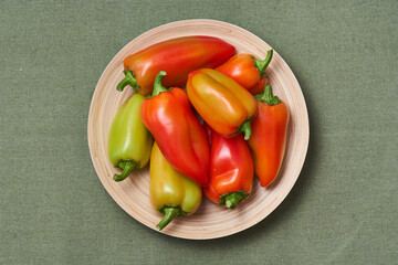 The colored pepper lies on a slide on a wooden plate on a green napkin. The view from the top.