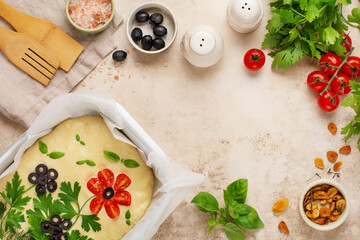 Homemade flower focaccia. Raw focaccia creatively decorated with vegetables on parchment paper. Sourdough dough. Decorated Italian bread. Top view.