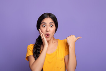 Excited indian woman pointing aside at copy space