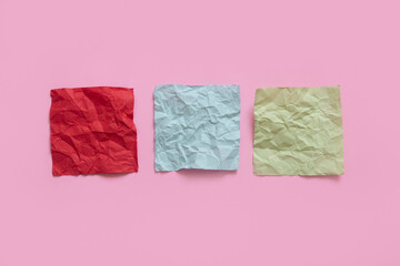three color crumpled papers on pink background  