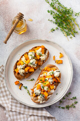 Baked pumpkin sandwich with dorblu cheese with blue mold, honey and thyme on a concrete old light background. Top view.