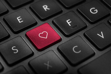 Close up of black and white keyboard with one red button with white heart outline in the middle.