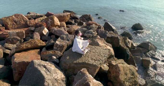 Mujer madura hace yoga sentada frente al sol con mascarilla covid-19