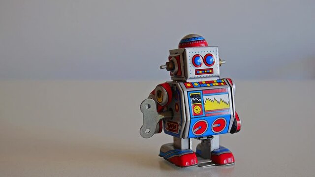 Funny colorful wind-up toy metal robot walks from the center to the right slowly. Full HD 1080p. Still frame.