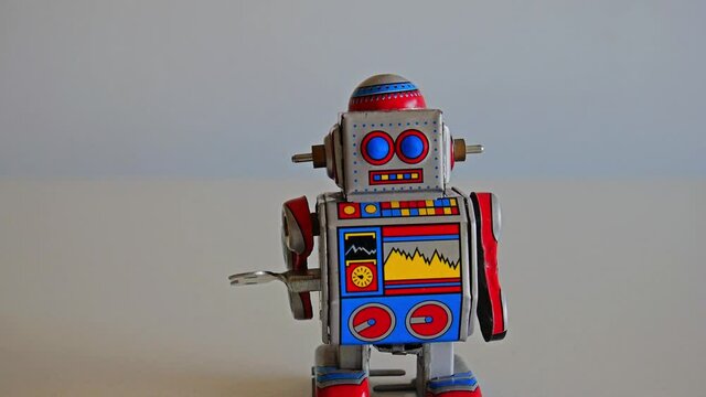 Funny colorful wind-up toy metal robot walks from the center to camera slowly. Full HD 1080p. Still frame.