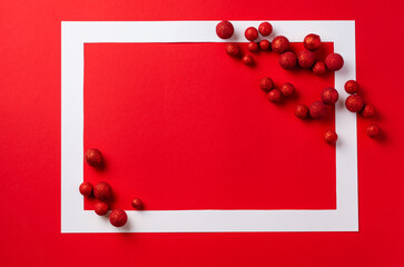 Christmas festive background. White frame with red Christmas decorations on red background. Place for text. Top view.