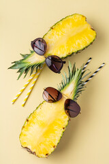 Fresh pineapple cut in two part, notebook or sketchbook and sunglasses on yellow background. Summer concept. Creative flat lay with copy space. Top view.