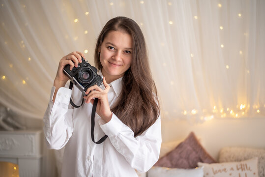 Sensual woman takes a photo of an old camera in white bed
