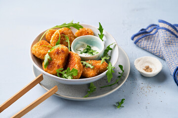 Vegetarian Nuggets with Vegan Dipping Sauce and rocket leaves on a light background with copy space, selective focus. Healthy Diet, Protein Vegetarian Meals concept, alternative meat products.