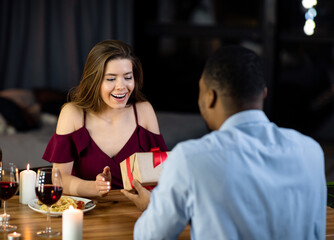 Black Man Surprising His Girlfriend With Gift During Romantic Dinner In Restaurant