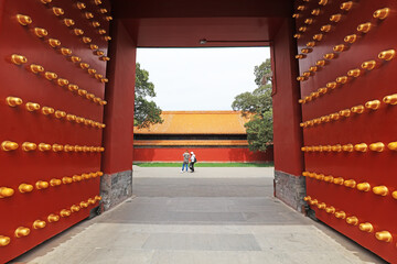 Visitors play in the red wooden palace gate in Ditan Park, Beijing, China