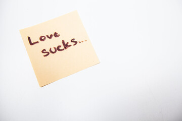 Love sucks written on yellow piece of paper, isolated