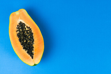 Papaya cut in half on blue background. Copy space.