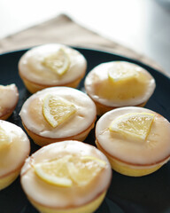 Moist and Sweet Lemon Butter Cake flavored with Lemon Juice Glaze Icing and Zest, garnished with a lemon slice. Soft and Sour Cream Lemon Dessert, putting on a dark blue plate.