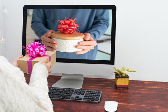 Virtual gift delivery. People exchanging gifts in videoconference. Computer with person on screen delivering gift.
