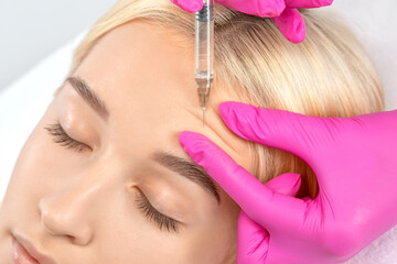 Cosmetologist makes rejuvenating anti wrinkle injections on the face of a beautiful woman. Female...
