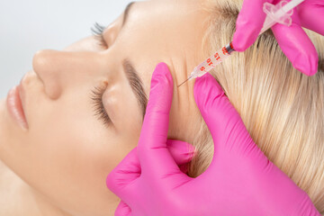 Cosmetologist makes rejuvenating anti wrinkle injections on the face of a beautiful woman. Female...