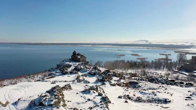 Aerial footage monastery  on frozen water and blue sky background. 
Ancient, Christian monastery near the lake of Sevan. It was built in 9-12 centuries. 