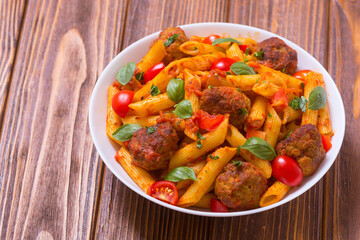 Italian penne pasta with meatballs and tomatoes