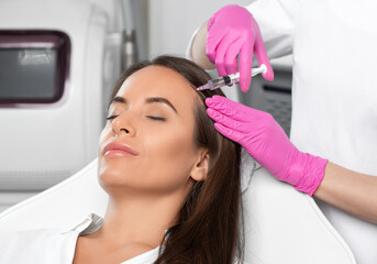 Cosmetologist makes rejuvenating anti wrinkle injections on the face of a beautiful woman. Female...
